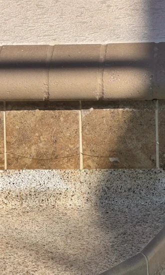 Cracks running across waterline tiles below the pool coping