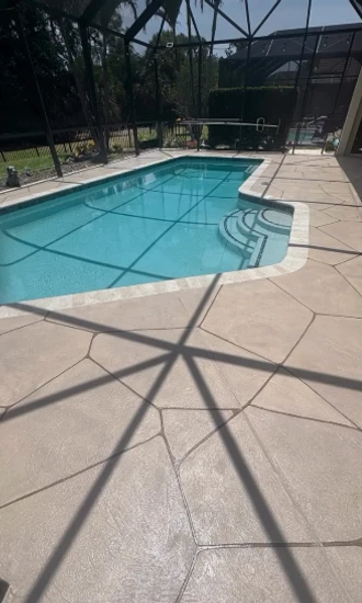 Renovated pool deck with a stone-pattern surface and renewed coping