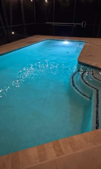 Underwater light illuminating a residential pool and curved steps at night