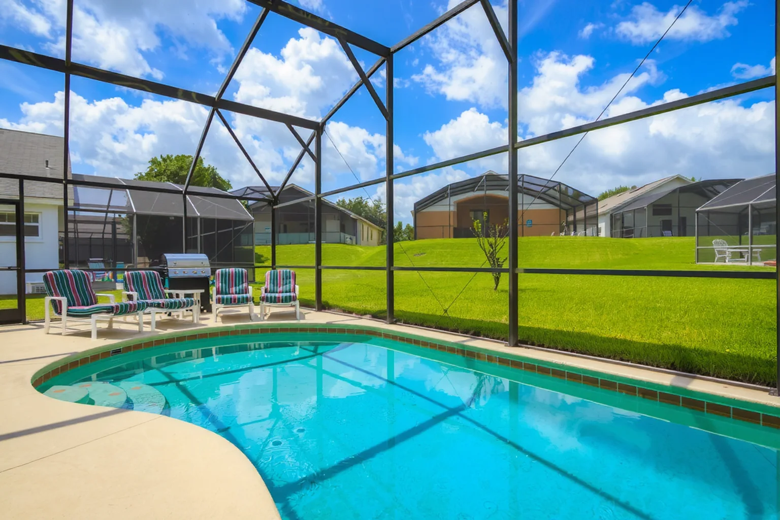 Curved inground pool with submerged entry steps inside a residential screen enclosure